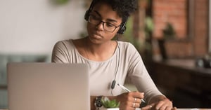 A higher ed student learning with headphones