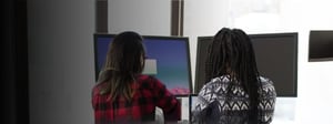 Staff augmentation and managed IT services concept showing two professionals collaborating at shared workstations, illustrating hands-on technical support, team extension models, and the contrast between in-house staff augmentation and fully managed IT service approaches.