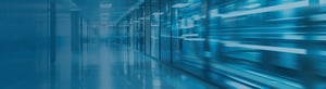 A sleek, blue-toned corridor lined with glass walls and server-like structures, with motion blur suggesting speed and data flow, representing high-performance digital infrastructure and modern enterprise technology.